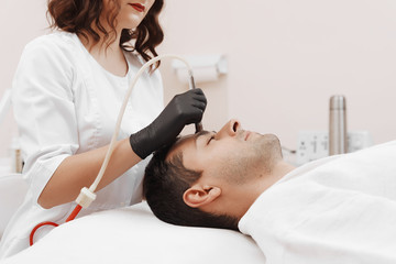 The cosmetologist makes the procedure Microdermabrasion