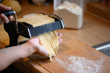 manually selfmade noodles pasta with machine on wood and flour