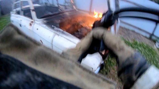 Extinguishing a burning car.Fire suppression.A firefighter puts water on the fire.Fire protection.
