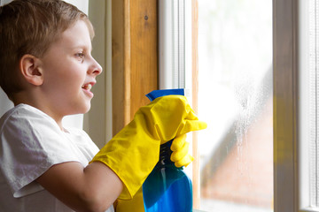 the boy in the yellow gloves washes a window