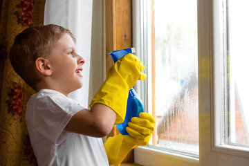 the boy in the yellow gloves washes a window