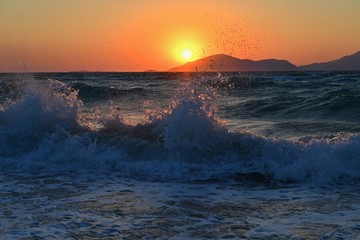Beautiful sunset with sea and waves. Natural colorful background. Concept for summer and sea vacation. Greece - island of Kos.