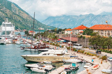 Ancient town Kotor with marina and yachts on the water, old stoned houses surrounded by mountains, Montenegro