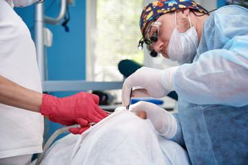 Hands of the surgeon of the dentist and the assistant with the instrument during the operation.