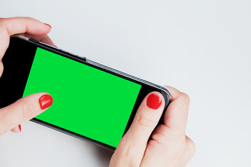 Female hands holding smartphone with green isolated screen. Mockup cellphone.