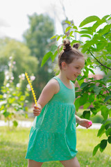 Cute girl plays on the green grass, outdoors, summer time, blurred background