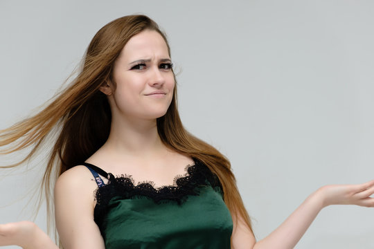 Concept close-up portrait of a pretty girl, young woman with long beautiful brown hair in a green t-shirt on a white background. In the studio in different poses showing emotions.