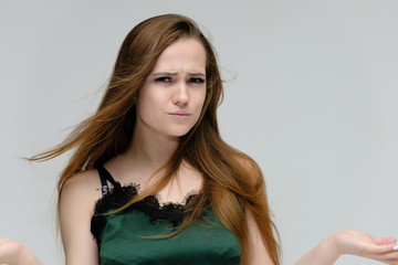 Fototapeta premium Concept close-up portrait of a pretty girl, young woman with long beautiful brown hair in a green t-shirt on a white background. In the studio in different poses showing emotions.