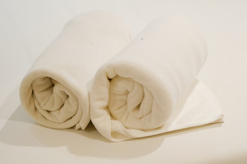 Two roll of white towel on bed