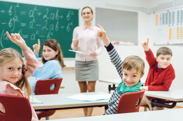 Schüler in der Klasse melden sich, um eine Frage zu beantworten 