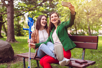 Frau und ihre beste Freundin mit verstauchtem Fuß machen ein Selfie