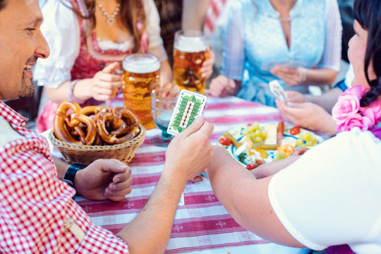 Freunde im Biergarten in Bayern spielen Schafkopf