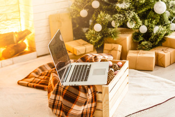 Laptop with empty screen on wooden, blur Christmas tree and gifts on background