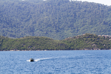 Obraz premium Boat on the background of mountains overgrown with forest.