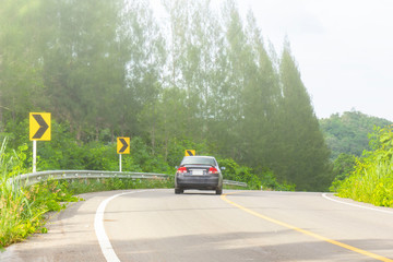 Black cars are running on the road with beautiful nature and fog.