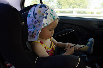 the child is sitting in a child car seat. A child in a hat and sunglasses.