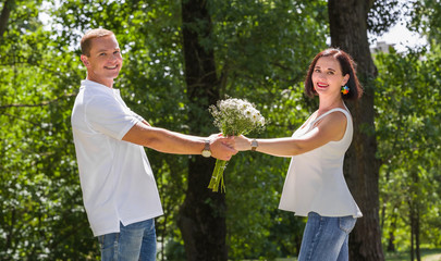 The young loving couple of people holds hands with a bouquet of flowers