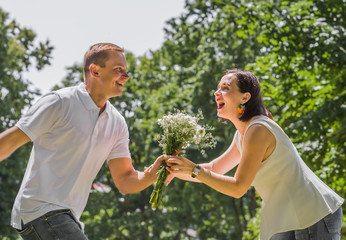 guy and the girl in a jump on a meeting each other with a bouquet of flowers