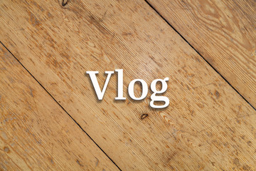 `Vlog` white text on a wooden home background. 