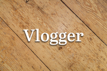 `Vlogger` white text on a wooden home background. 