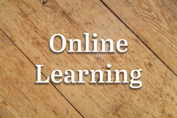 `Online Learning` white text on a wooden home background. 