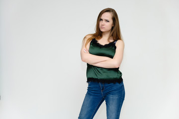 Concept portrait above the knee of a pretty girl, a young woman with long beautiful brown hair and a green t-shirt and blue jeans on a white background. In studio in different poses showing emotions.