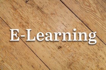 `E-learning` white text on a wooden home background. 
