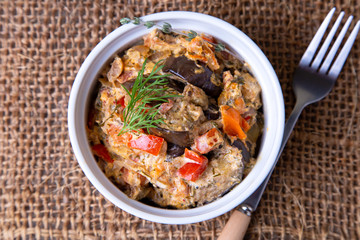 Eggplants with tomatoes, bulgarian red (sweet) pepper, onion, dill and sour cream. Vegetarian dish. Close-up.