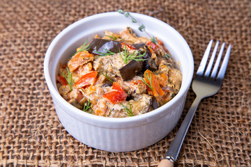 Eggplants with tomatoes, bulgarian red (sweet) pepper, onion, dill and sour cream. Vegetarian dish. Close-up.