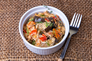 Eggplants with tomatoes, bulgarian red (sweet) pepper, onion, dill and sour cream. Vegetarian dish. Close-up.