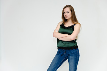 Concept portrait above the knee of a pretty girl, a young woman with long beautiful brown hair and a green t-shirt and blue jeans on a white background. In studio in different poses showing emotions.
