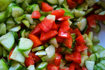 Fresh healthy vegetables, finely chopped green cucumbers and red pomade for summer salad, ingredients for salad.
