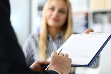 Smiling female real estate agent offering male visitor document to sign