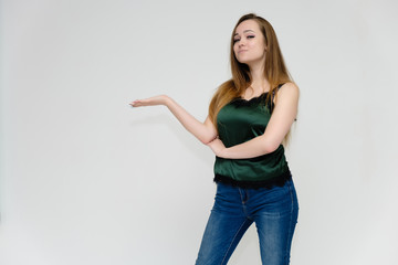 Concept portrait above the knee of a pretty girl, a young woman with long beautiful brown hair and a green t-shirt and blue jeans on a white background. In studio in different poses showing emotions.