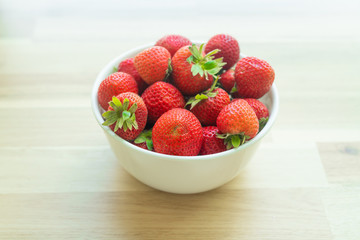 strawberries in bowl on wooden table