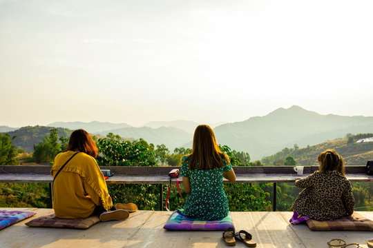 Asian girl relax with landscape nature mountain in the morning, Sit on balcany looking beautiful sunrise on the peak of mountain, Asian women wear jacket in winter with green nature view