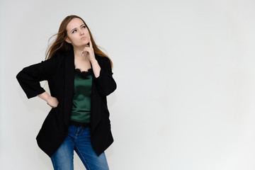 Concept portrait above the knee of a pretty girl, a young woman with long beautiful brown hair and a black jacket and blue jeans on a white background. In studio in different poses showing emotions.