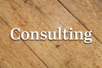 'Consulting' white text on a wooden background. 