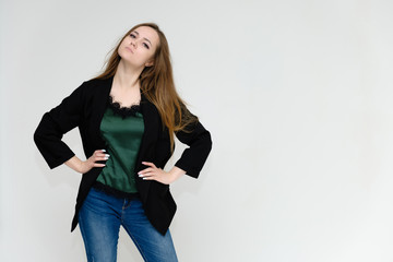 Concept portrait above the knee of a pretty girl, a young woman with long beautiful brown hair and a black jacket and blue jeans on a white background. In studio in different poses showing emotions.