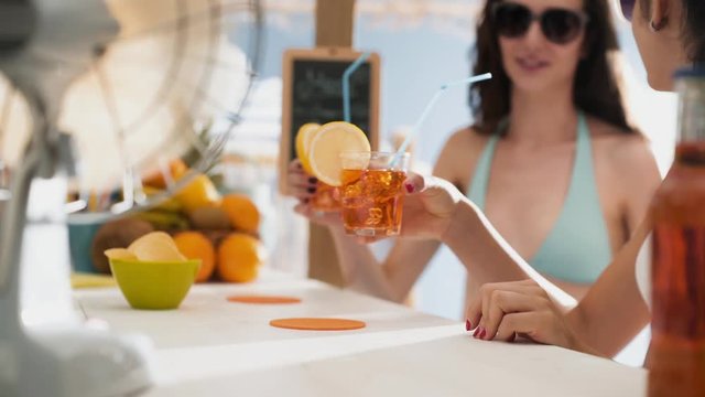 Cheerful young women having a drink at the beach