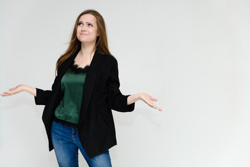 Concept portrait above the knee of a pretty girl, a young woman with long beautiful brown hair and a black jacket and blue jeans on a white background. In studio in different poses showing emotions.