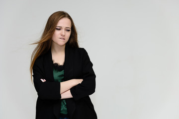 Concept portrait for the waist of a pretty girl, a young woman with long beautiful brown hair and a black jacket and blue jeans on a white background. In studio in different poses showing emotions.