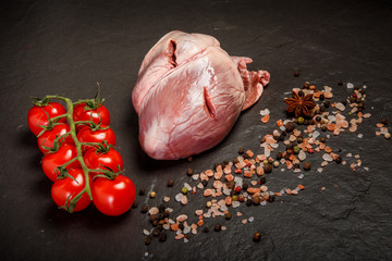 top view pork raw heart served with spices and tomatoes