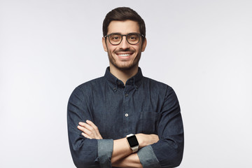 European man wearing spectacles and smartwatch looking at camera with smile, isolated on gray...
