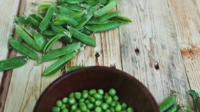 closeup green peas in brown dish, on wooden table.