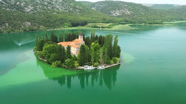 Beautiful island of Visovac on lake in Krka national park with old monastery, Dalmatia, Croatia, circle drone shot around the island