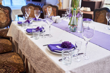 Table setting with white plates, wineglasses, cutlery and flowers on table, copy space. Place setting at wedding reception. Table served for wedding banquet in restaurant
