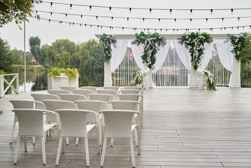 Place for wedding ceremony with wedding arch decorated with palm leaves, orchid flowers and floral...