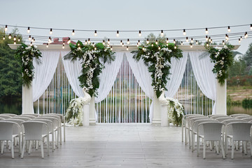 Place for wedding ceremony with wedding arch decorated with palm leaves, orchid flowers and floral...
