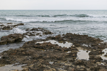 Coast sea with weak waves crashing onto the rocks